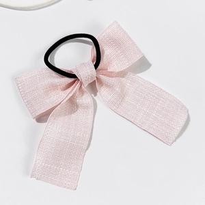 Dettaglio di un elastico per capelli con fiocco rosa e texture glitterata scintillante