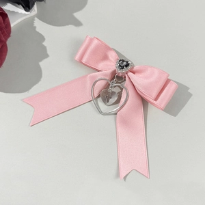 Barrette à nœud en satin rose avec pierre noire en cœur et pendentif croix argenté