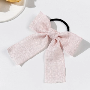 Elastico per capelli con fiocco rosa e trama metallica su sfondo bianco minimalista