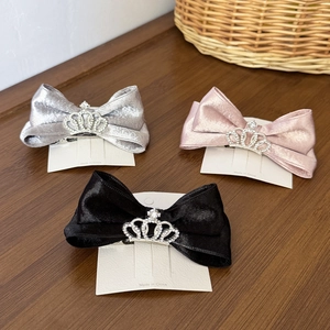 Detailed view of three bow hair clips with rhinestone crowns on a card display
