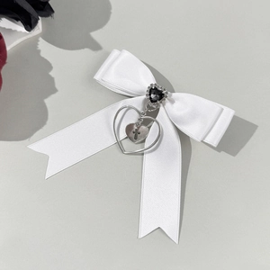 Détail d'un nœud en satin blanc avec gemme cœur noire et pendentif croix en argent poli