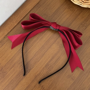 Gros plan d'un élégant serre-tête avec nœud en satin bordeaux sur table en bois