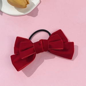 Elegant red velvet bow hair tie with elastic band on a pink background