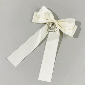 Detail view of cream satin bow hair clip with silver heart cross pendant ornament