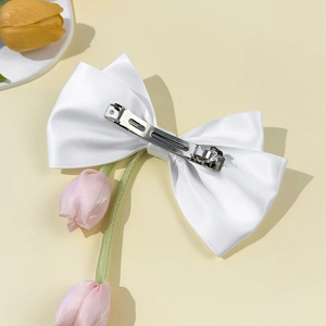 Détail de la barrette à cheveux en satin blanc avec clip en métal et texture soyeuse