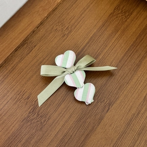 Detail einer grünen Ballett-Stil Haarschleife mit Herzakzenten auf Holzgrundlage