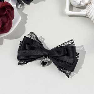 Détail de pince à cheveux gothique avec nœud en dentelle noire et pendentif cœur en strass
