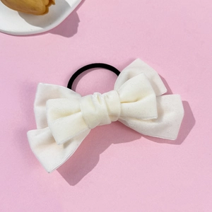 Detailed macro view of white velvet bow hair scrunchie with durable elastic band