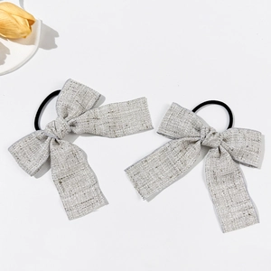 Dettaglio di elastici per capelli con fiocco in tweed grigio chiaro su sfondo bianco