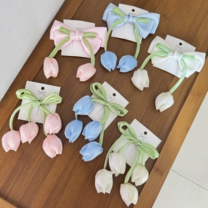 Dettaglio di vari fiocchi per capelli con tulipani in rosa, blu e bianco su basi di carta
