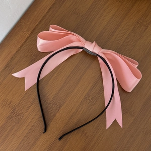 Détail d'un serre-tête rose en satin avec un nœud multicouche et une texture soyeuse