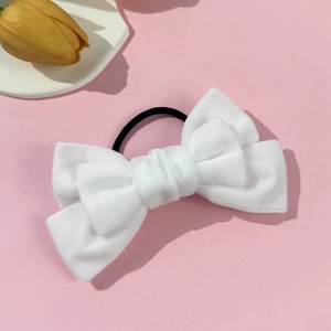 Detail of white velvet bow hair tie with elastic band on a pink aesthetic background