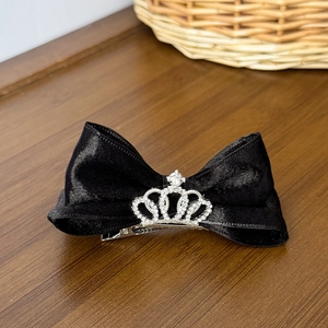 Detail of elegant black satin bow hair clip with a sparkling silver crown and rhinestones