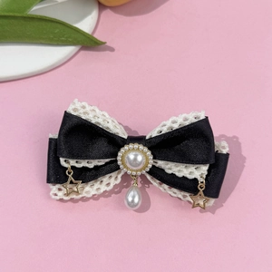 Detalle del pasador Lolita con lazo negro, encaje blanco, perlas y estrellas doradas