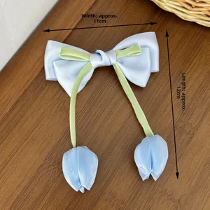 Dettaglio del fermaglio a fiocco con tulipani blu e nastri su legno, 11x12cm