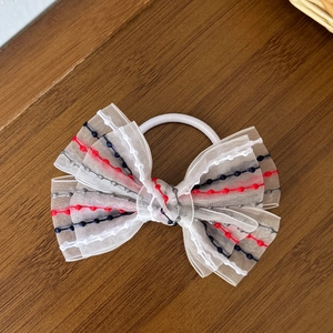 Detailed macro view of layered sheer mesh bow hair tie with colorful embroidered dots