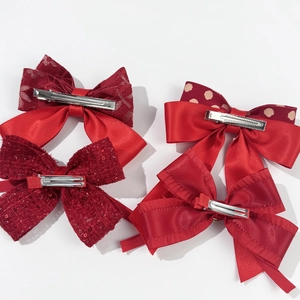Set of four red festive bow hair clips featuring lace, satin, and tweed textures with metal clips