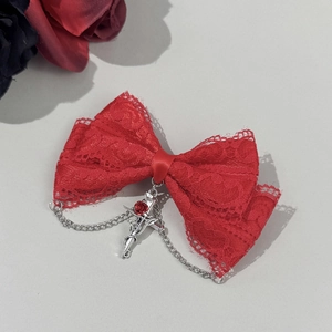 Detalle de lazo de encaje rojo con colgante de cruz plateada de estilo gótico dark