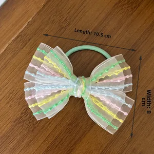 Detailed view of sweet rainbow ribbon bow hair tie showing 10.5cm length on wood surface