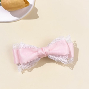 Pink silk bow hair clip with white lace trim and sweet aesthetic on beige background