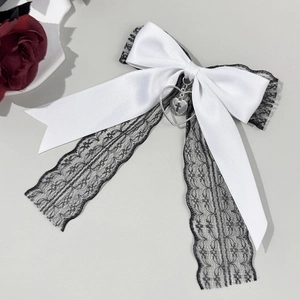 Détail d'un grand nœud en satin blanc avec dentelle noire et pendentif cœur argenté