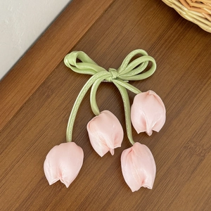 Dettaglio di un fermaglio per capelli in raso verde con quattro ciondoli a tulipano rosa