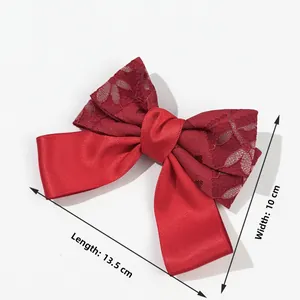 Detail of red festive ribbon bow hair clip showing 13.5cm length and lace texture