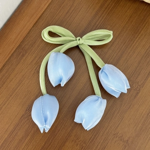 Dettaglio del fermaglio a tulipano con fiocco in raso verde e boccioli in tessuto blu