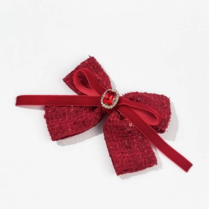 Close-up of red tweed and velvet bow hair clip with a ruby rhinestone centerpiece