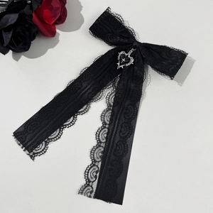 Détail du nœud en dentelle noire gothique avec pendentif cœur croisé et des roses