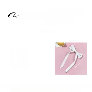 Detail view of a 5.7g white ribbon bow hair clip with long streamers, size 11.5x19cm