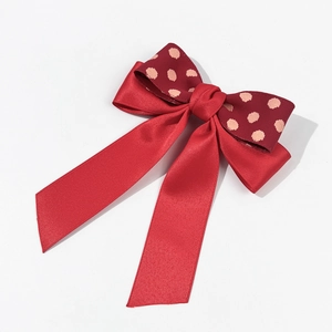 Close-up of double-layered red satin ribbon bow hair clip with pink polka dot pattern