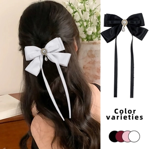 Detail view of elegant satin bow hair clip with pearl center and long ribbon streamers