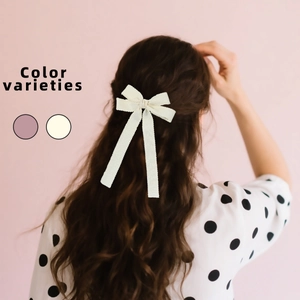 Elegant bow hair clip with long ribbons on brown wavy hair for a stylish look