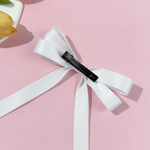 Elegant white satin ballet bow hair clip with long ribbons on pink background