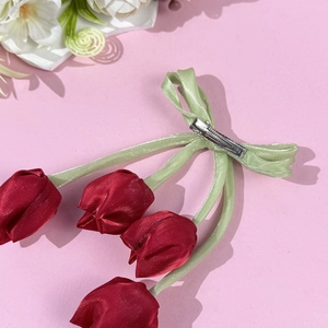 Dettaglio del fermaglio per capelli a tulipano in seta rossa con fiocco verde