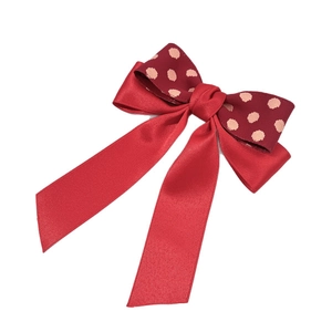Red bow hair clip with satin ribbon and polka dot pattern for elegant festive styling