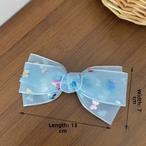 Detail of light blue mesh bow hair clip with butterfly pattern, size 13cm by 7cm