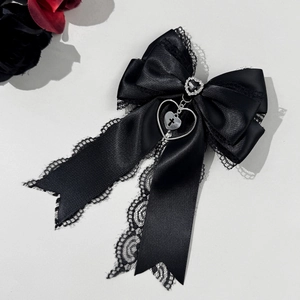 Details der schwarzen Spitzen-Haarschleife mit Strass-Herz und Kreuzanhängern
