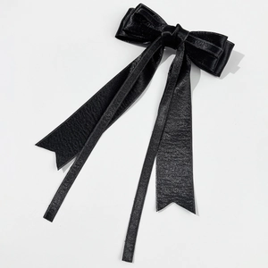 Detailed view of the smooth black silk satin double-layered bow hair clip with long ribbons