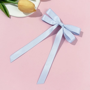 Light blue ballet-style satin ribbon bow hair clip on a pink aesthetic background