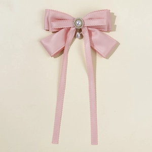 Detail of pink satin bow hair clip with pearl center and dangling teardrop pendant