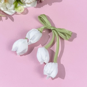 Dettaglio del fiocco di raso e dei ciondoli a tulipano in verde e bianco delicato