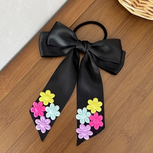 Détail d'un chouchou en satin noir avec nœud et broderies de fleurs colorées élégantes