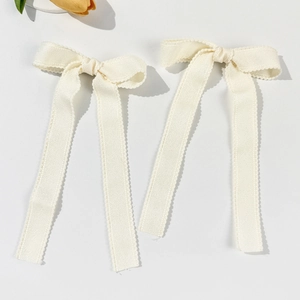 Detail of cream lace bow hair clips with long ribbons and delicate wave edges