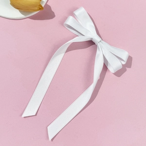 Detailed view of elegant white satin ribbon bow hair clip with long flowing streamers