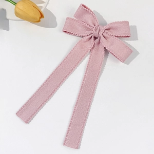 Close-up of elegant pink bow hair clip with decorative lace edges and long ribbons