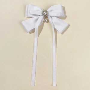 Detail of white satin bow hair clip with faux pearl center and dangling pearl tassel