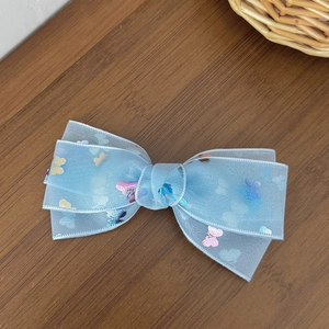 Detail view of light blue mesh hair clip with colorful butterfly print on wood background