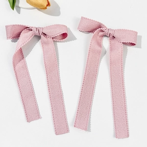 Detail of pink lace ribbon hair bows with delicate scalloped edges and long streamers
